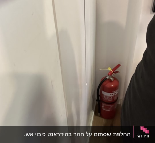 מטף כיבוי אש אדום מותקן בפינת חדר